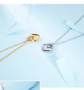 Close-up of gold and silver heart-shaped lock pendants on a light blue background