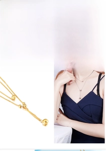 Détail du collier double en acier titane avec pendentif boule en or et argent