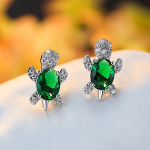 Close-up of turtle stud earrings with green emerald stone and sparkling zircon details