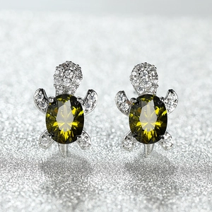 Macro detail of turtle stud earrings featuring olive green stones and sparkling pavé crystals
