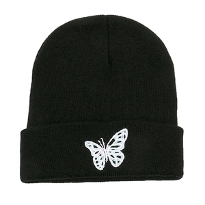 Close-up of butterfly embroidery detail on the cuff of a black ribbed knit beanie hat