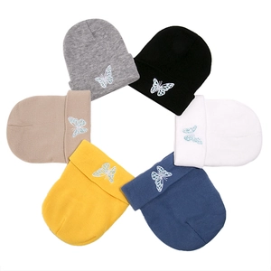 Detailed view of knitted beanies in six colors featuring elegant butterfly embroidery