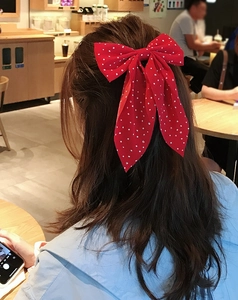 Detail view of large red polka dot bow hair clip with long ribbons worn on hair
