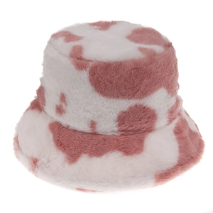 Détail d'un bob en peluche à motif vache avec une texture de fausse fourrure rose et blanc