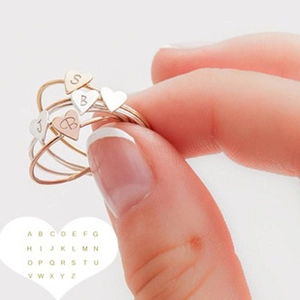 Detailed view of stacked heart rings in gold, silver and rose gold with custom letter A-Z