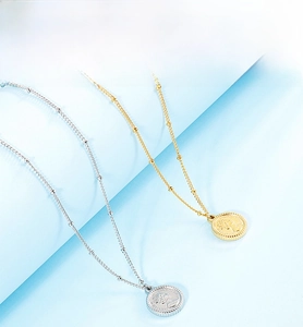 Close-up of gold and silver coin pendants with embossed portraits on fine bead chains