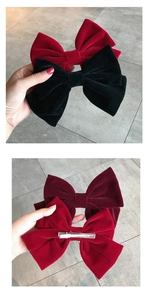 Detailed view of large velvet bow hair clips in red and black with metal alligator clips