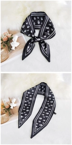 Close-up of black silk scarf with white skull print and striped border detail