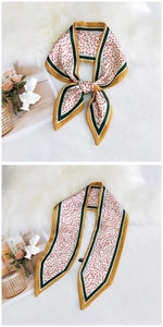 Detail of silk-feel scarf with red leaf pattern tied in a bow on soft white fur