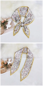 Detail of silk scarf with purple floral print and yellow stitching on white fur background