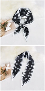 Detail of a black twilly scarf with white lip print on a soft plush background