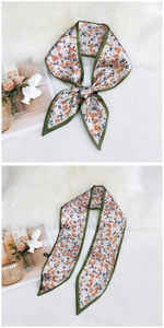 Detailed view of floral silk neck scarf tied in a bow on a soft white fur texture