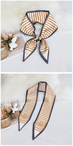 Detail of orange striped twilly silk scarf with dark blue piping and satin finish