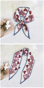 Detail of silk skinny scarf with burgundy hearts and Hilda branding on white faux fur