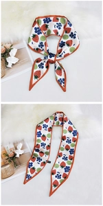 Detailed close-up of a narrow silk scarf with strawberry and berry fruit patterns