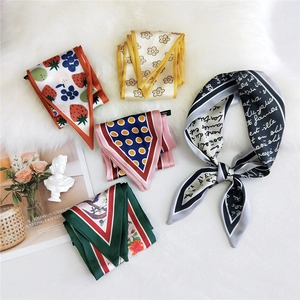 Group of elegant narrow silk scarves with floral and dot patterns on plush white background