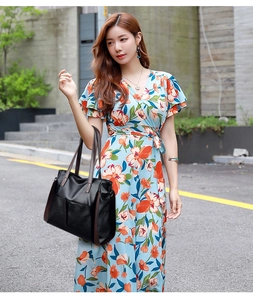 Detailed view of a black soft leather tote bag with brown handles on a floral dress