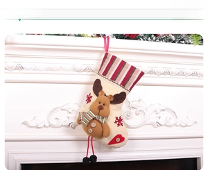 Detail of a velvet Christmas stocking with a 3D reindeer doll hung on a fireplace
