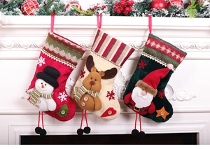 Three decorative Christmas stockings with snowman and reindeer hanging on a white fireplace