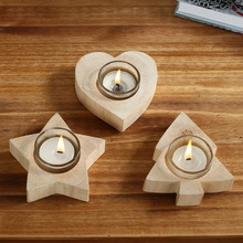 Top view of three wooden candle holders in heart, star, and tree shapes with glass inserts