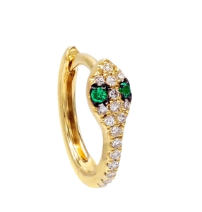 Macro side view of gold snake-shaped jewelry with white zircon and green gemstone eyes