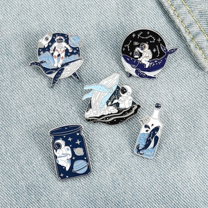 5-piece astronaut and whale enamel pin set on blue denim background for backpacks