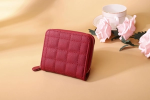 Detail of dark red quilted leather mini wallet with gold zipper and diamond pattern