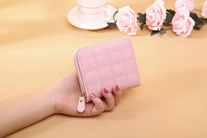 Pink quilted short wallet held by hand featuring soft leather and gold zipper detail