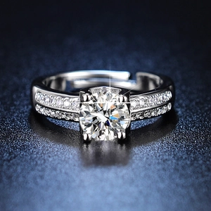 Detail of a sparkling one-carat round cut moissanite ring with six-prong setting on a dark surface