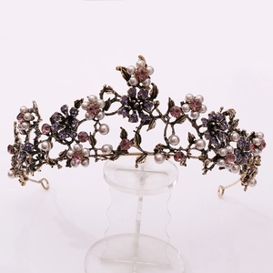 Detailed close-up of vintage golden crown with purple rhinestones and white pearls