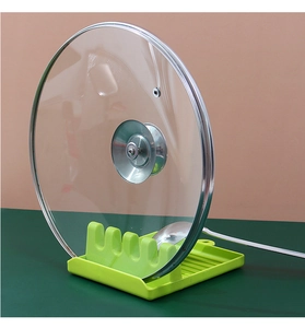 Macro view of green kitchen lid holder with wave slots holding lid and spoon