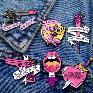 Detail of six pink feminist enamel pins displayed on a blue denim jacket pocket