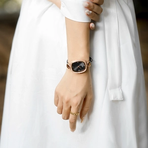 Elegant rose gold oval watch with black dial and diamond bezel on female model
