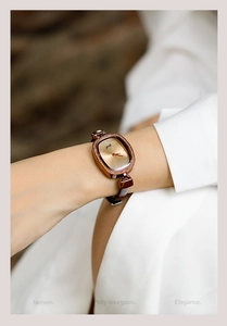 Detail view of women's oval gold watch with rhinestone bezel and brown leather strap