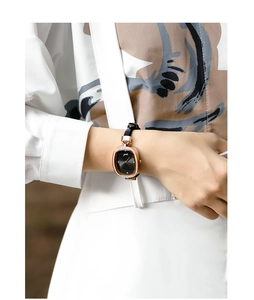 Close-up of a women's square watch with a rose gold rhinestone case and black leather strap