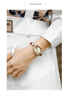 Close-up of small oval rose gold watch with diamond bezel and wine red leather strap