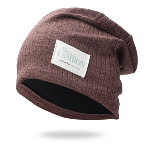 Detail of dark brown ribbed knit beanie featuring a white fabric label and soft inner lining