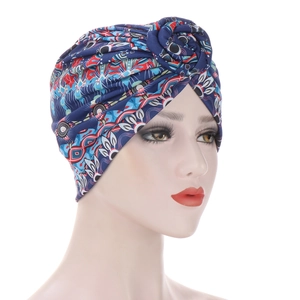 Detail of blue turban hat featuring ethnic print and twisted top on a model