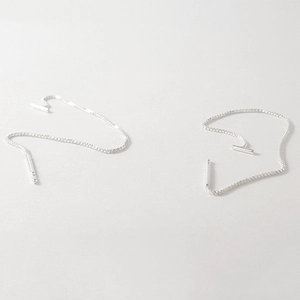 Detail of silver box chain tassel earrings showing smooth metal texture and sleek design