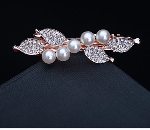 Close-up of rose gold hair clip with white pearls and sparkling rhinestone leaves