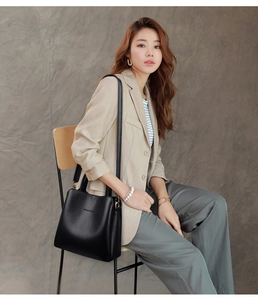 Detail of classic black lychee leather bucket bag with embossed lettering on a model