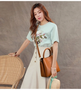 Close-up of a women's brown leather crossbody bag with stitching detail on a fashion model