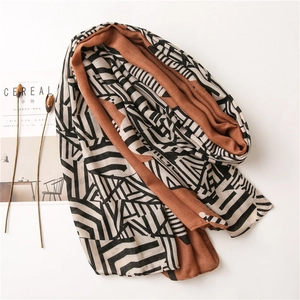Detail of a lightweight double-sided scarf showing geometric patterns and terracotta solid color
