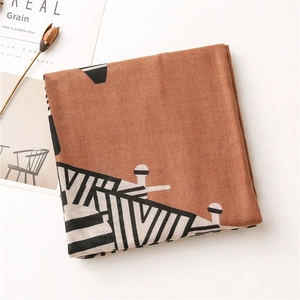 Detail of caramel scarf featuring geometric patterns and fine woven fabric texture