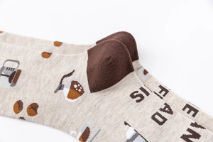 Macro detail of beige cotton socks with brown heel and coffee-themed knit patterns