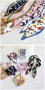 Close-up of narrow silk scarves in various patterns like floral and heart on white fur