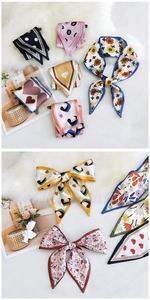 Close-up of assorted heart and floral pattern satin scarves on a plush white surface