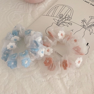 Macro view of organza scrunchies with delicate floral daisy embroidery and soft fabric texture