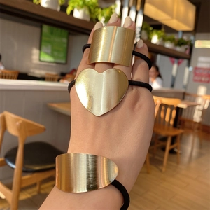 Close-up of golden geometric metal hair bands with heart and rectangle charms on hand
