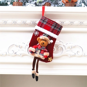 Detail eines roten Weihnachtssockens mit Bärenpuppe und Karomuster am Kamin